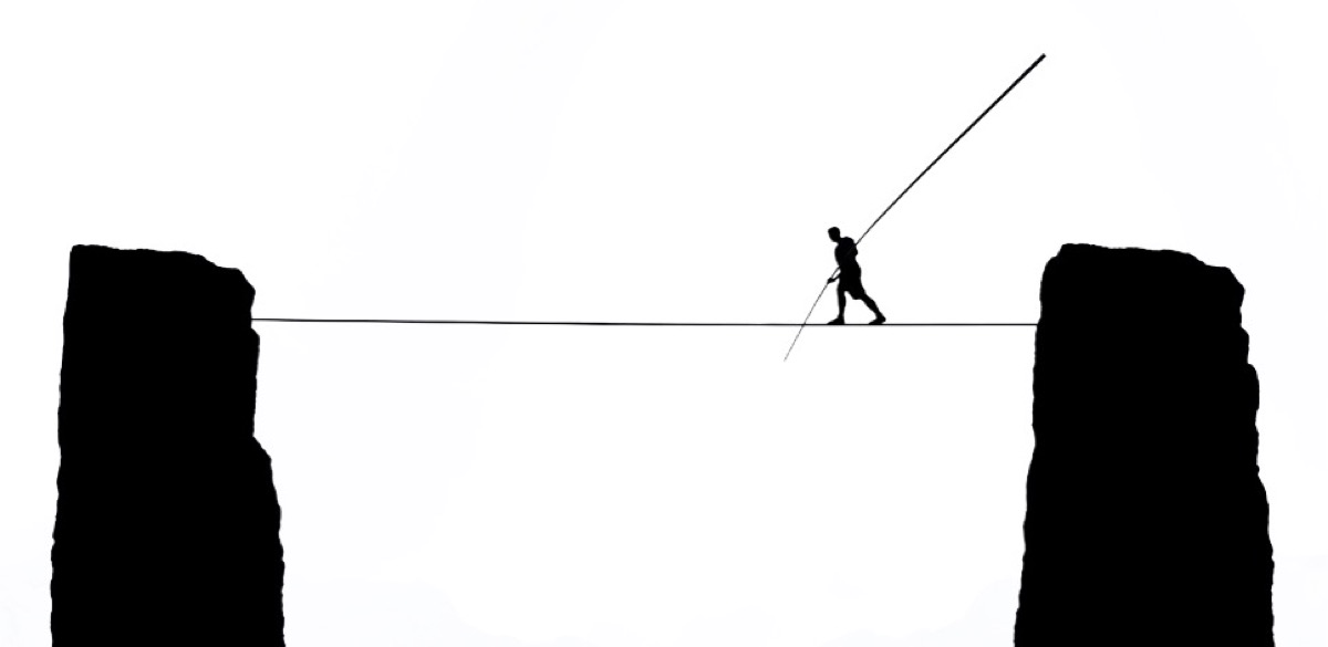 Man walking tightrope over canyon